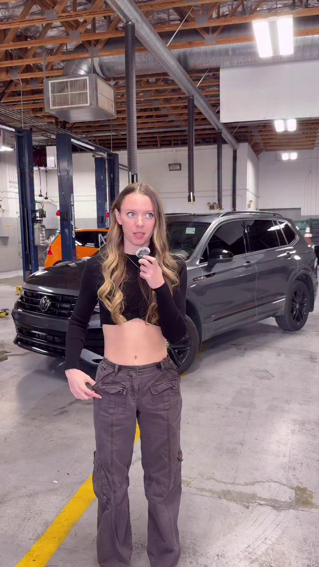 Kaytea presenting beside her Volkswagen Tiguan in the workshop